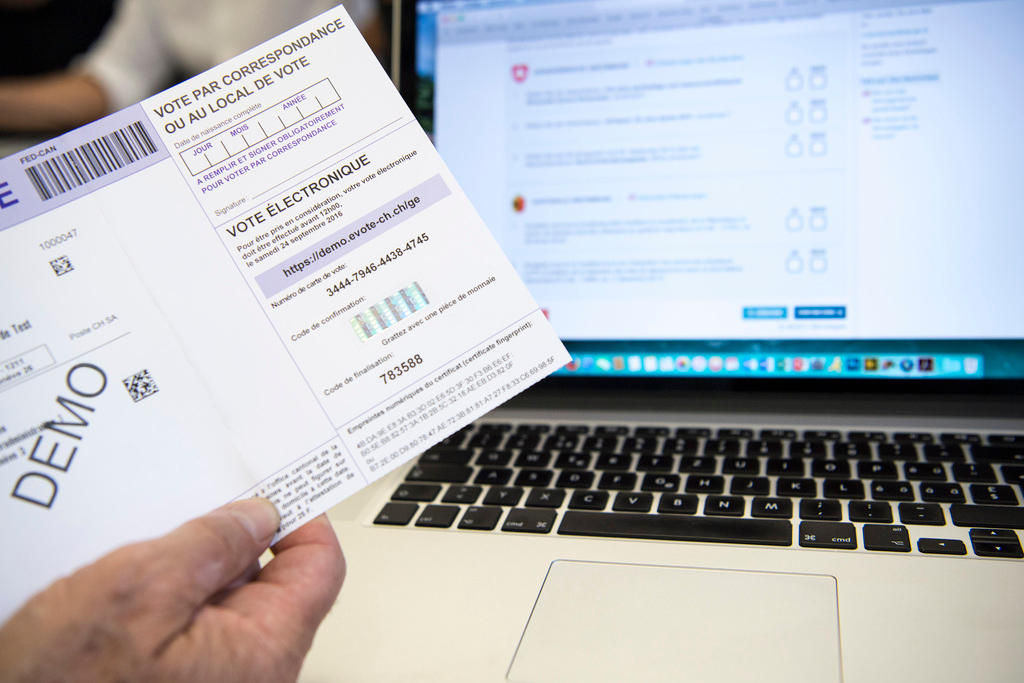 Una scheda di dimostrazione con codici per il voto online tenuta in mano davanti a un computer.