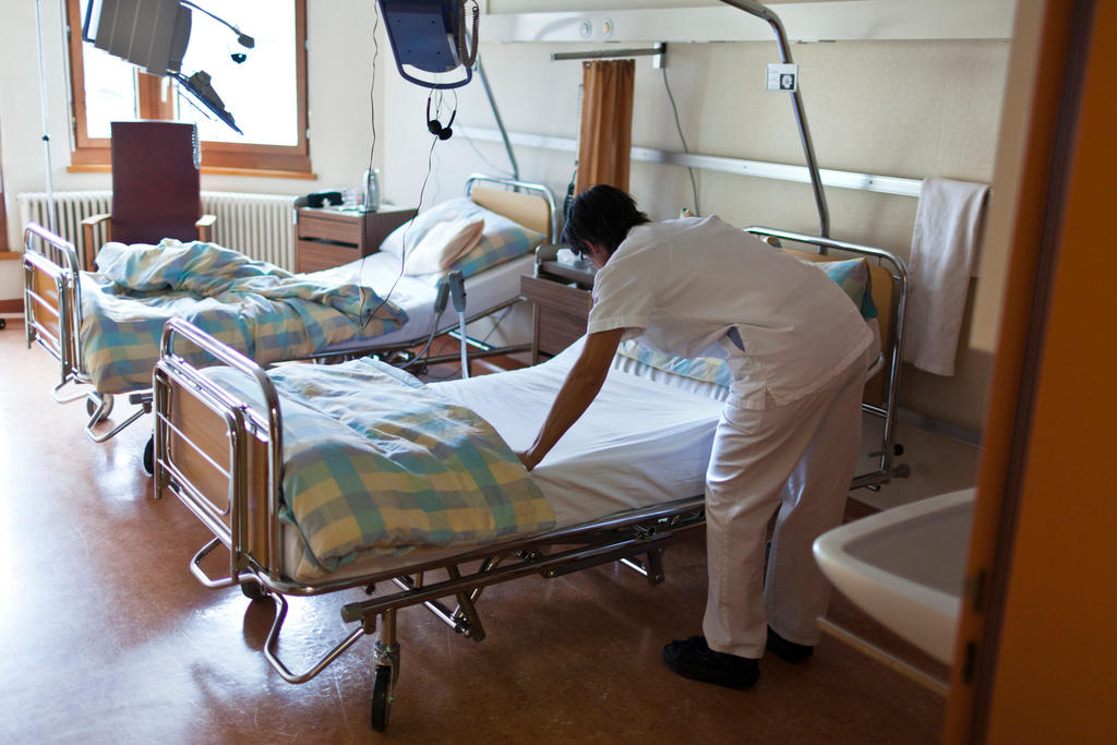 A nurse makes a hospital bed.