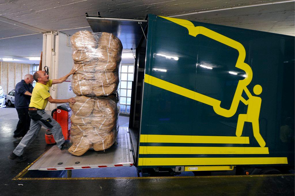 Two men loading a truck with large parcels.