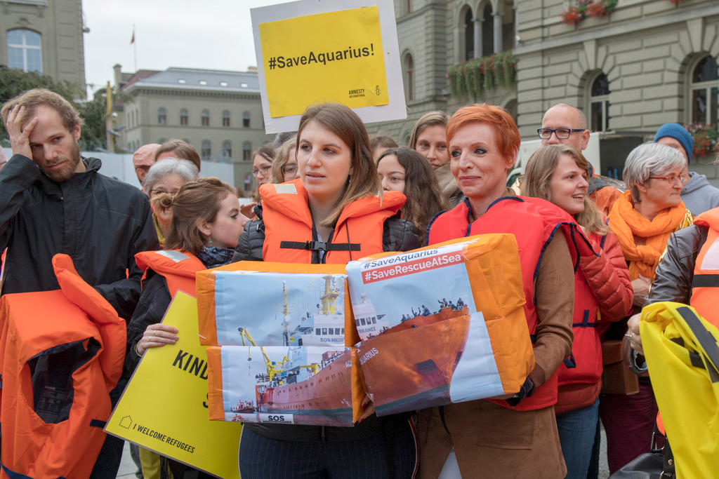 People wearing life jackets and carrying banners outside the Swiss parliament buildings