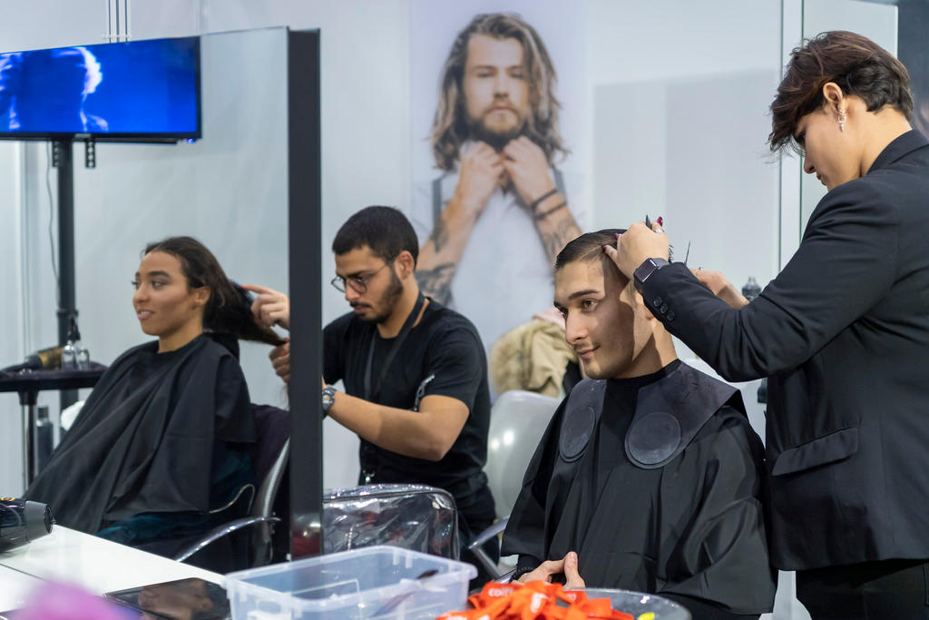 A man and woman cut the hair of customers