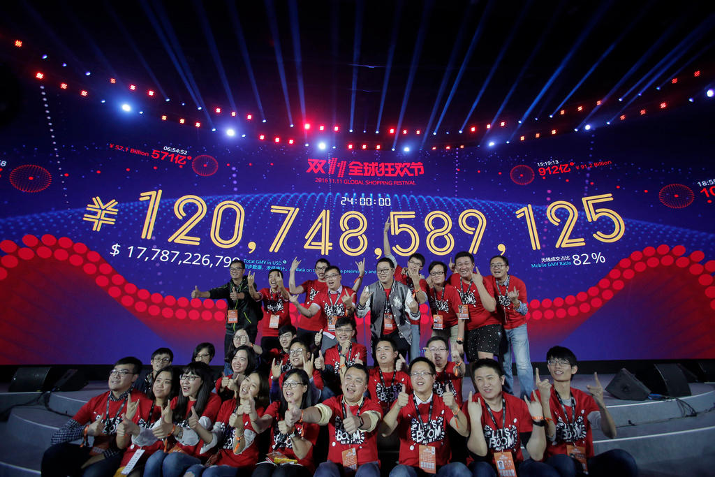 独身の日セールの売上高を表示したパネルとアリババ従業員