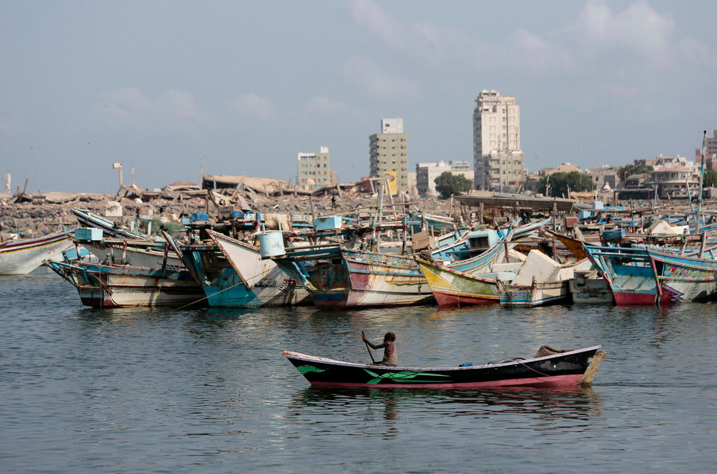 A fisherman paddles his boat past destroyed buildings on the coast of the port city of Hodeida