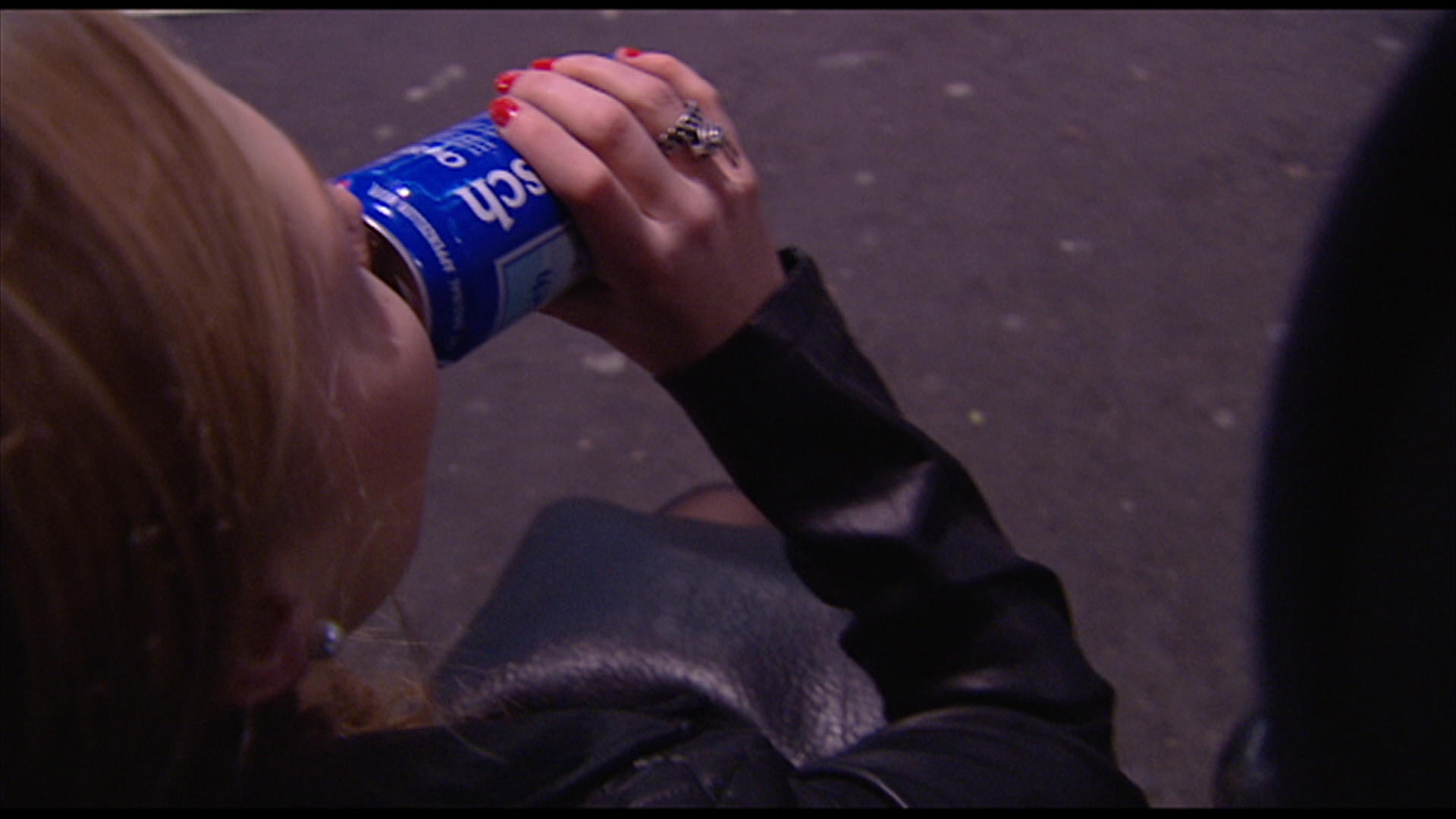 Young woman drinking beer in the street