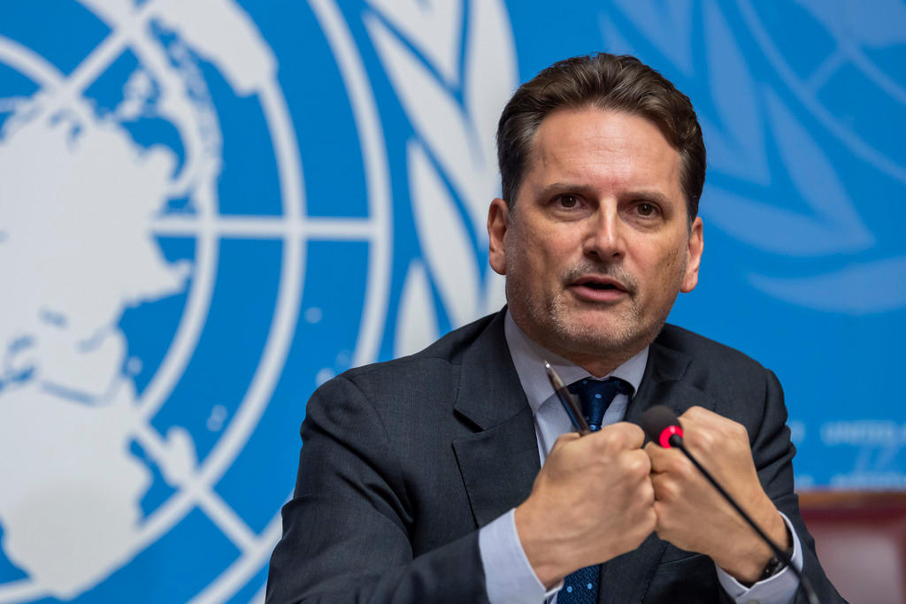 رجل يتحدث لوسائل الإعلام وفي الخلفية يُرى علم الأمم المتحدة