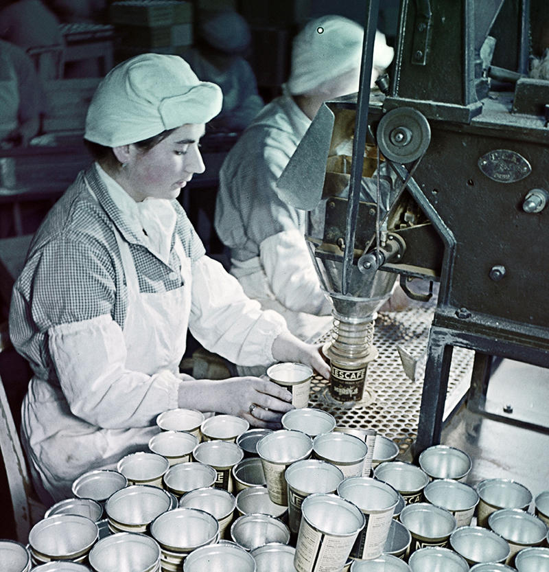 Fabrikarbeiterinnen füllen Blechdosen mit Nescafé-Pulver.