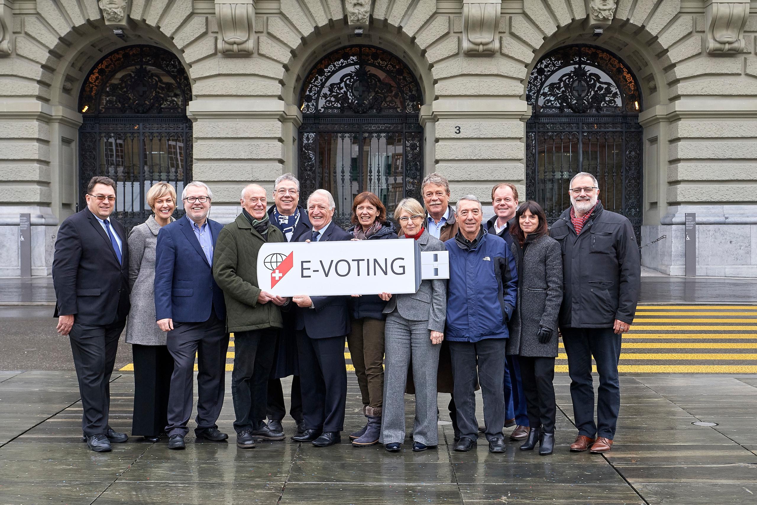 delle persone tengono un cartello su cui è scritto e-voting