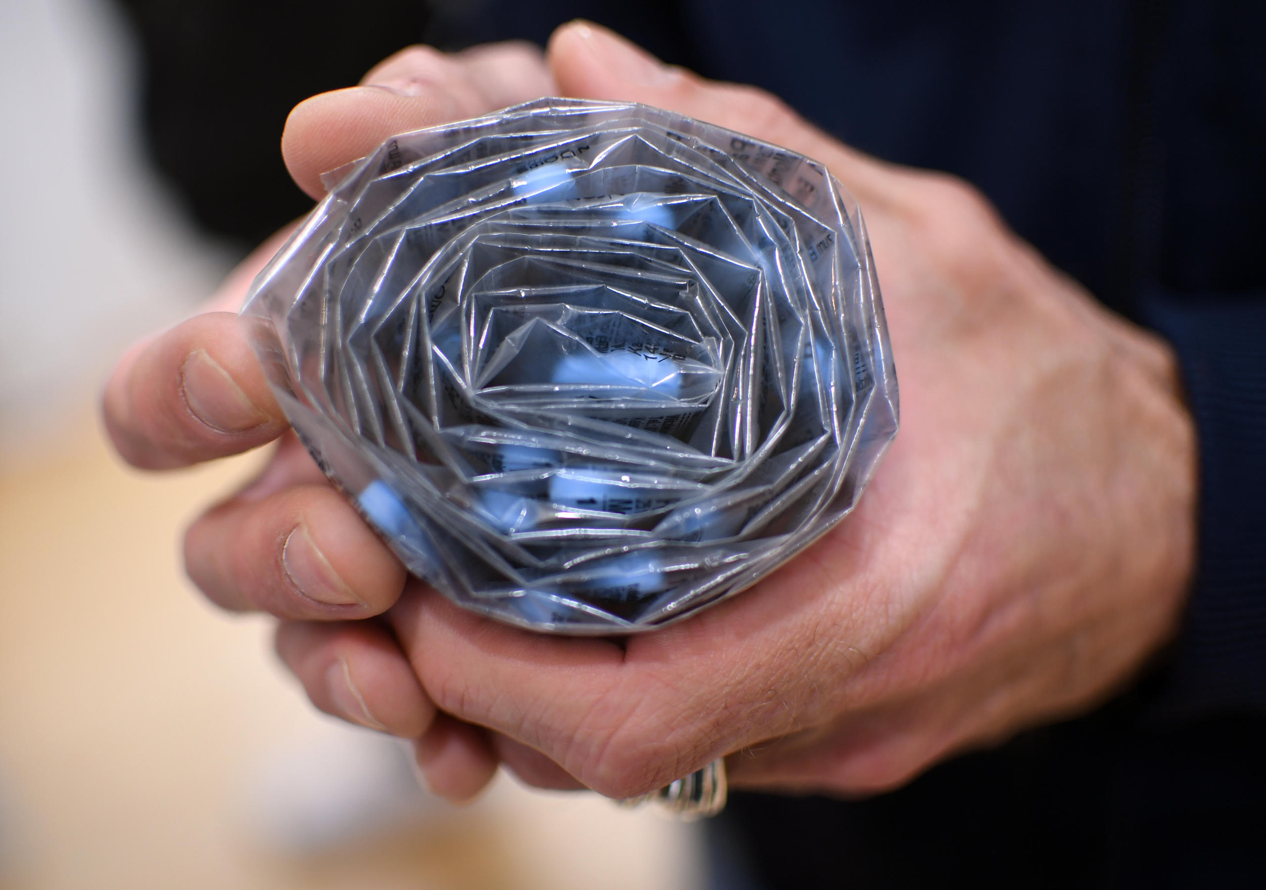 Zwei Hände halten eine Blisterpackung mit blauen Pillen drin