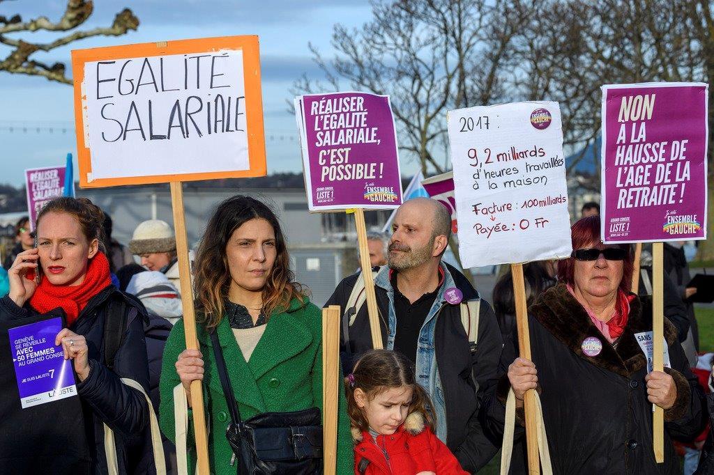 Manifestantes con pancartas que exigen igualdad salarial