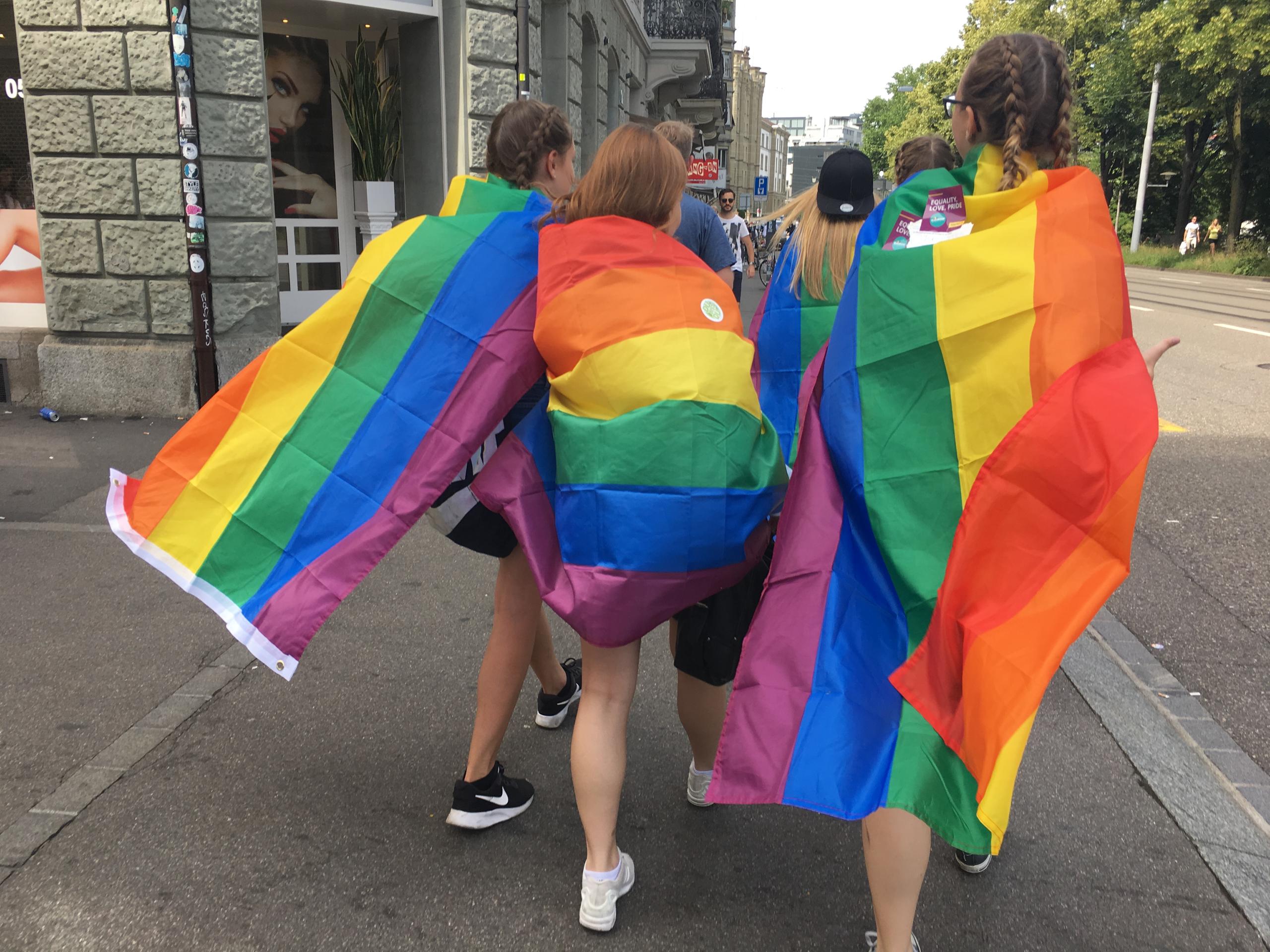 三个身披彩虹锦旗的女孩