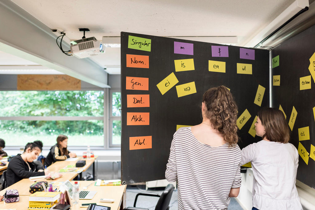 Schülerinnen an der Wandtafel mit lateinischen Wörtern