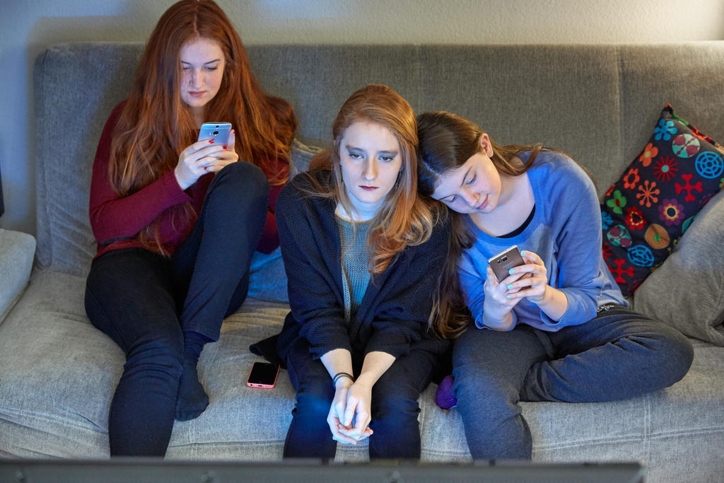 three young girls with smartphones