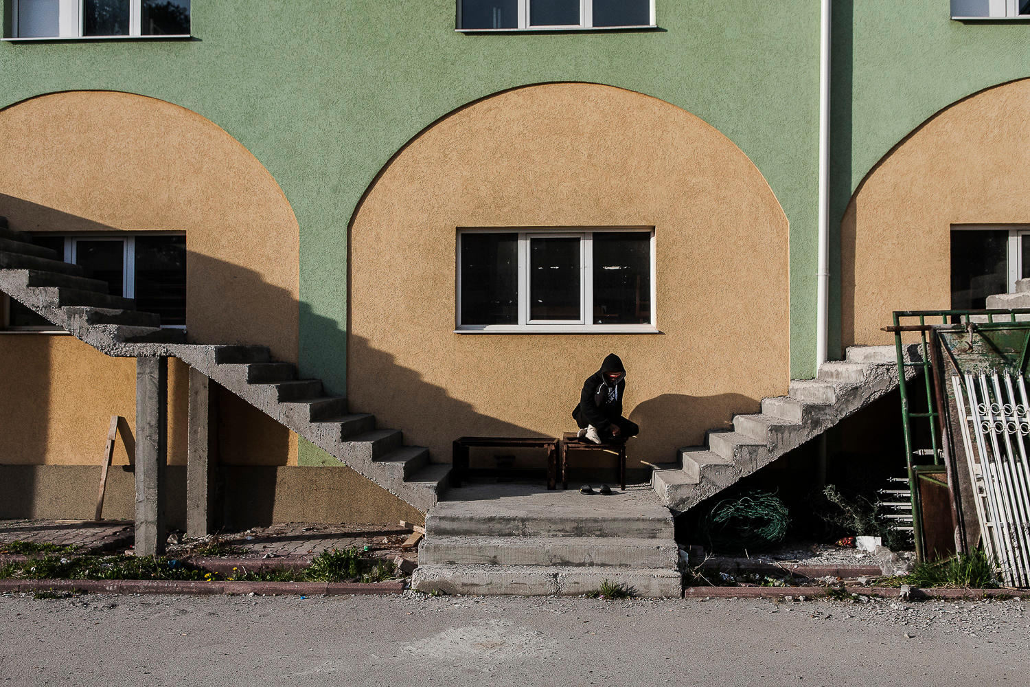 Steps leading up the side of the facade of a building painted green and sand colours.