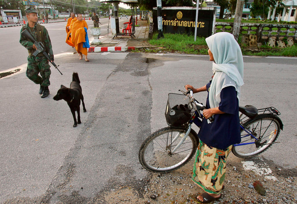 An einer Strassenkreuzung begegnen sich ein Soldat, eine Muslimin und buddhistische Mönche.