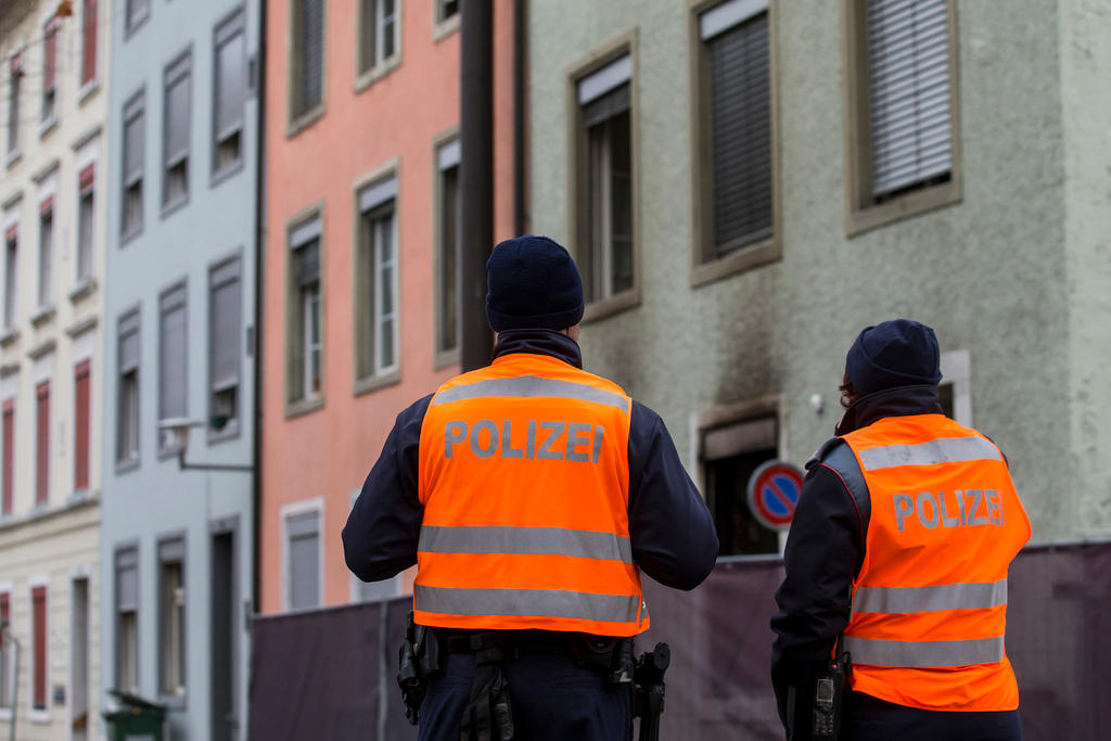 due poliziotti all esterno di un palazzo bruciato