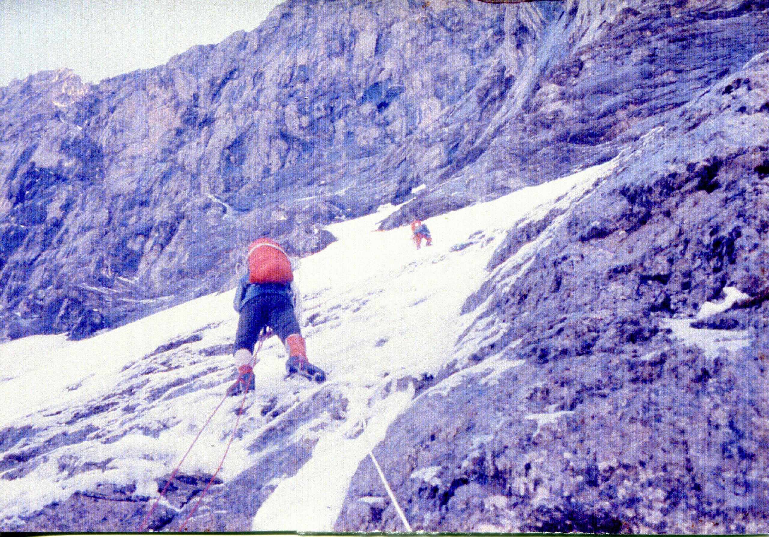 Looking up the north face at two climbers on ropes