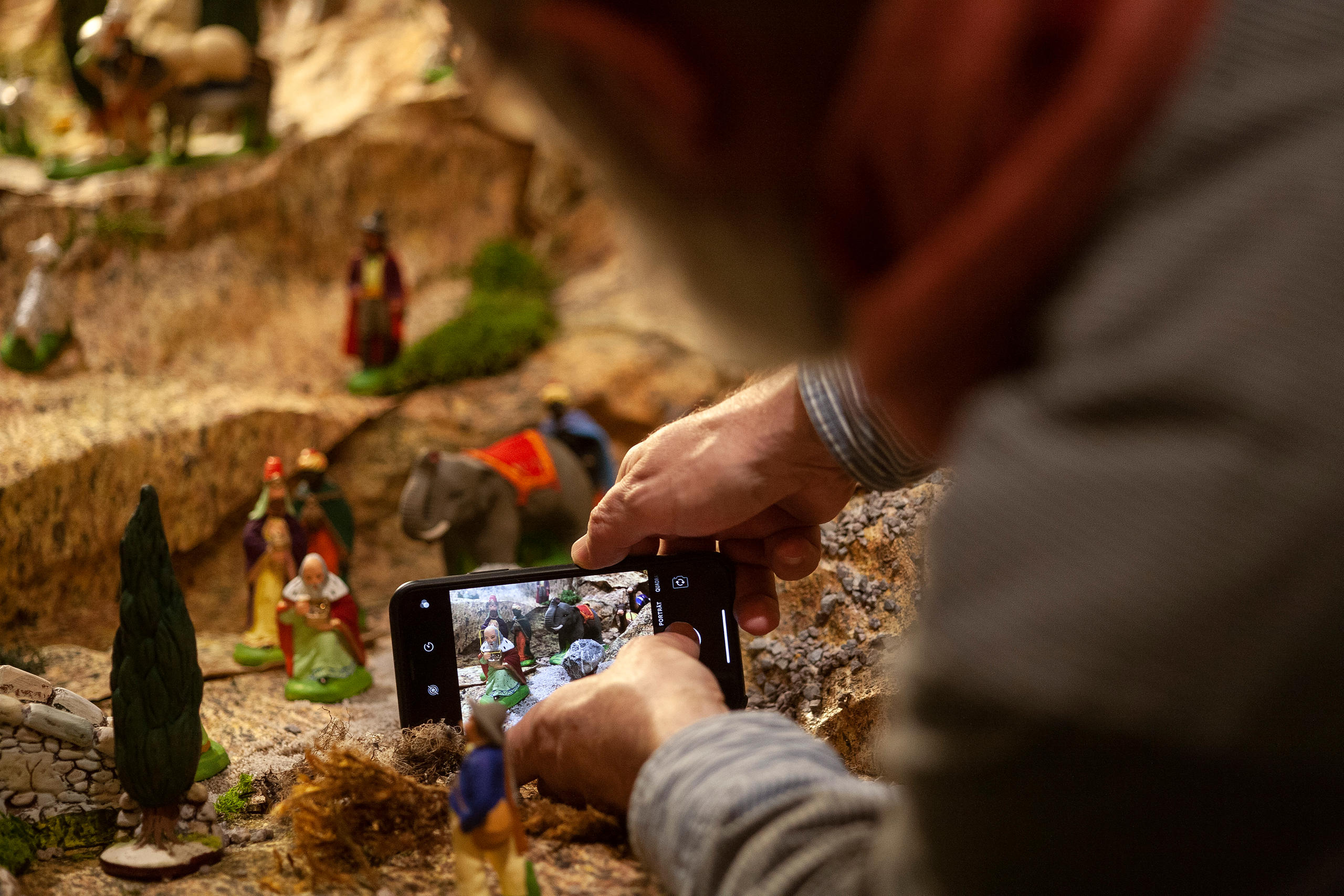 uomo fotografa le statuine con il cellulare