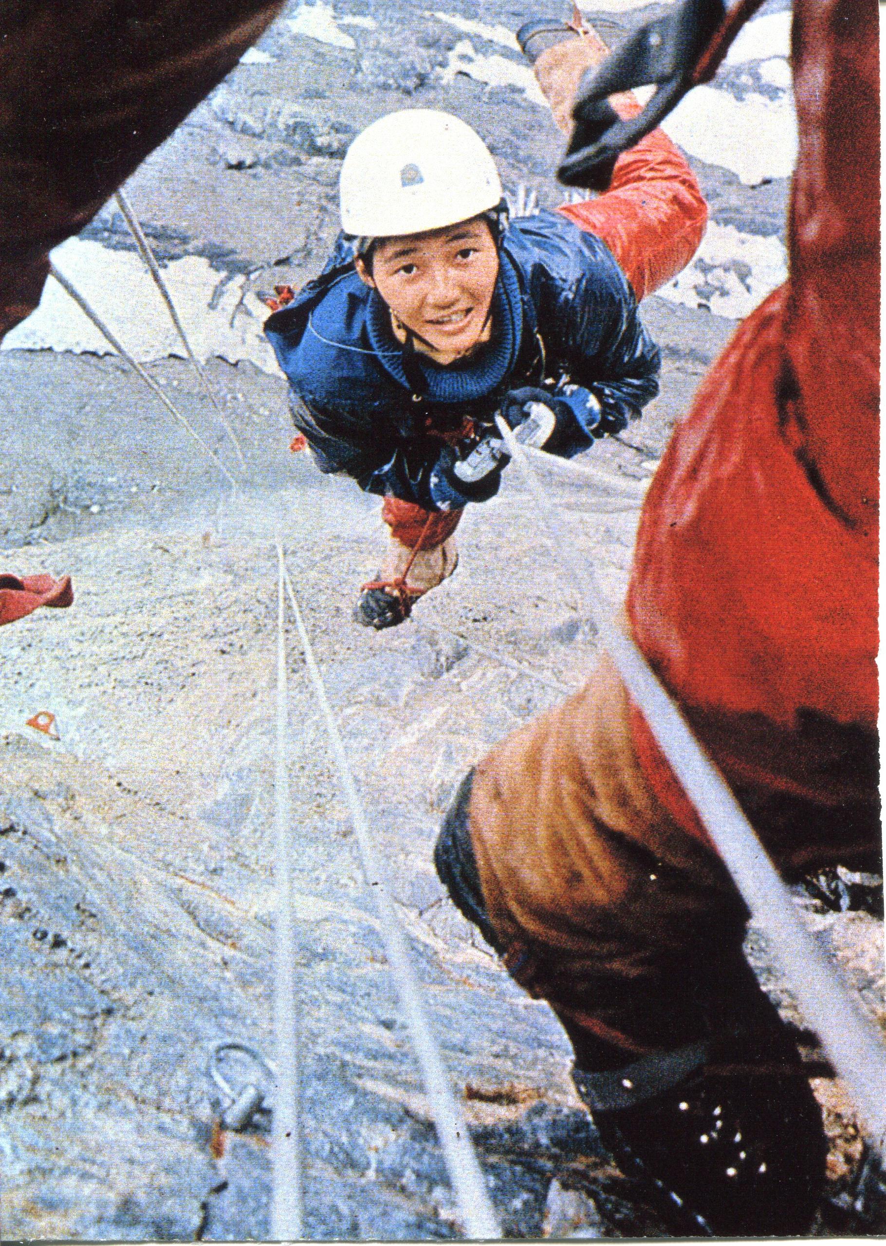 Una escaladora japonesa atada a una cuerda mirando hacia arriba para sacar la foto