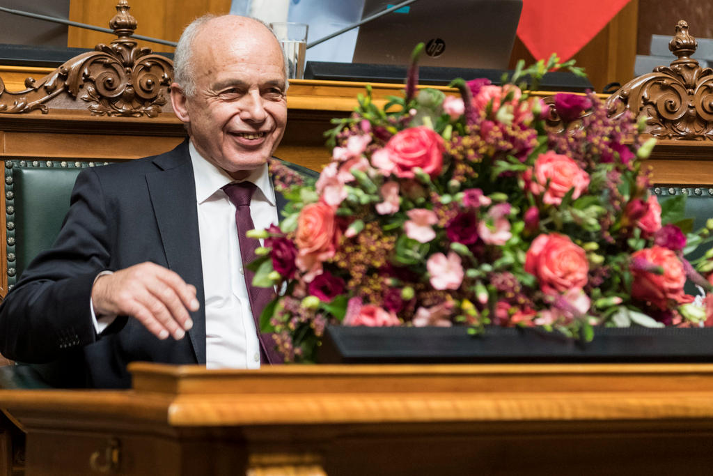 Ueli Maurer sits behind a bouquet of flowers in the parliamentary chamber