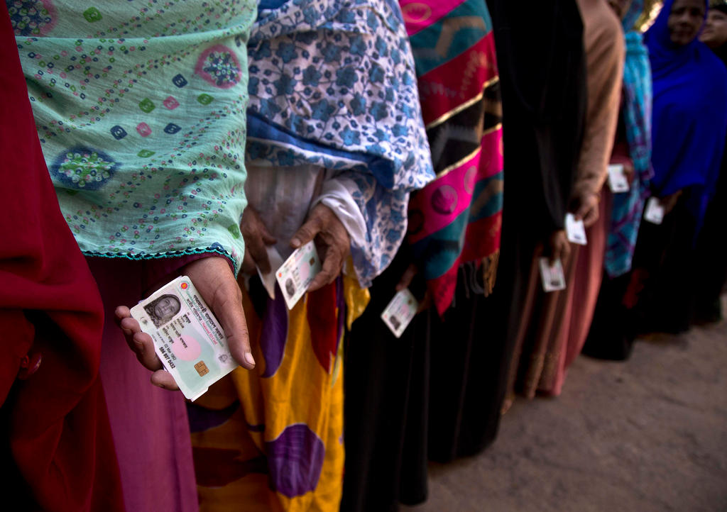 Scialli di donne in coda, che tengono in mano ognuna la sua carta d identità, viste di tre quarti