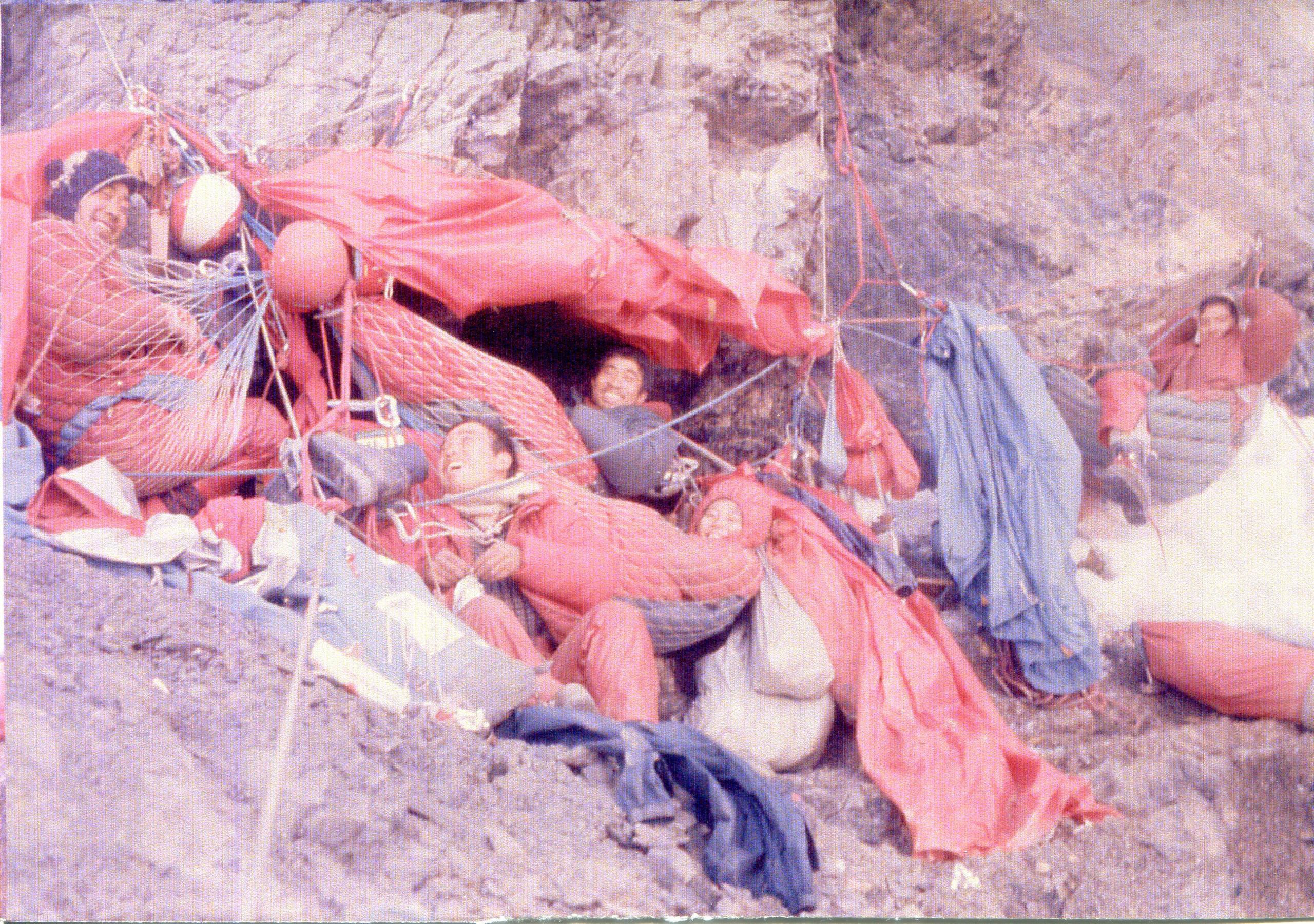 Climbers in sleeping bags on rockface