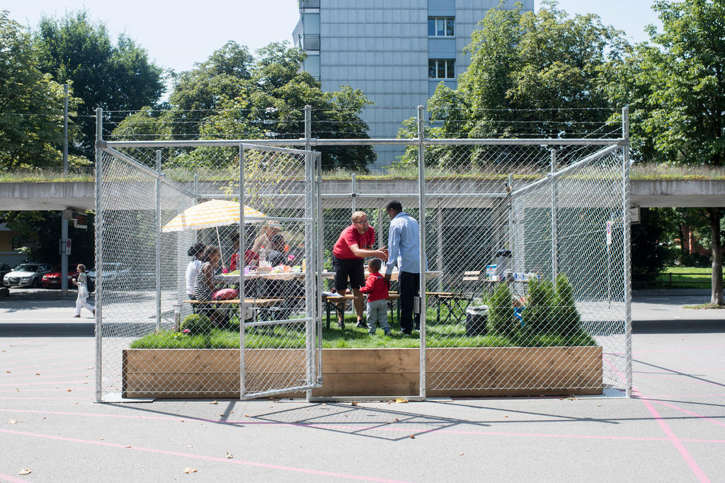Ein Mann empfängt in seiner Kunstinstallation, ein umzäuntes Gartenstück, Asylbewerber