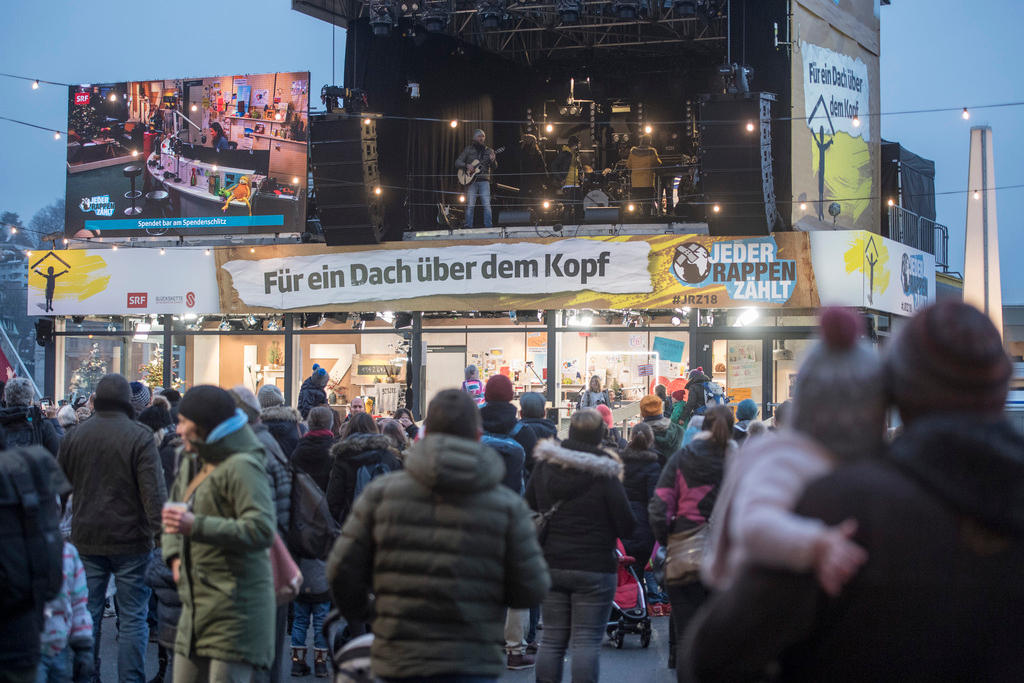 Crowd of people standing around a glass container withe radio TV studio