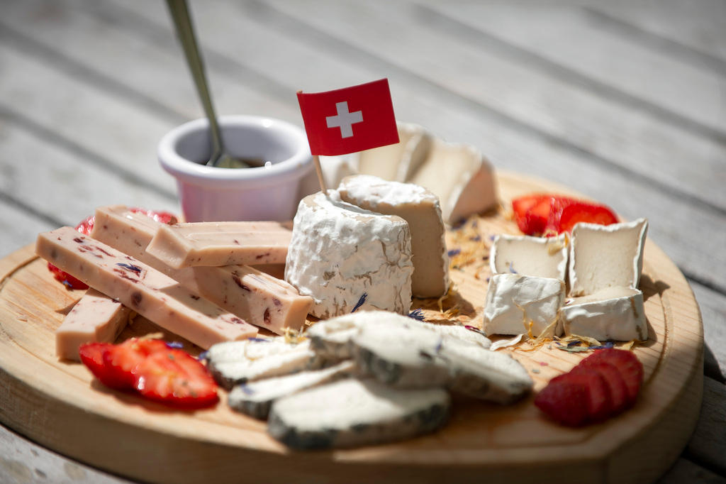 Diversi tipi di quello che, apparentemente, è formaggio, presentati su un tagliere con una mostarda e una bandierina svizzera