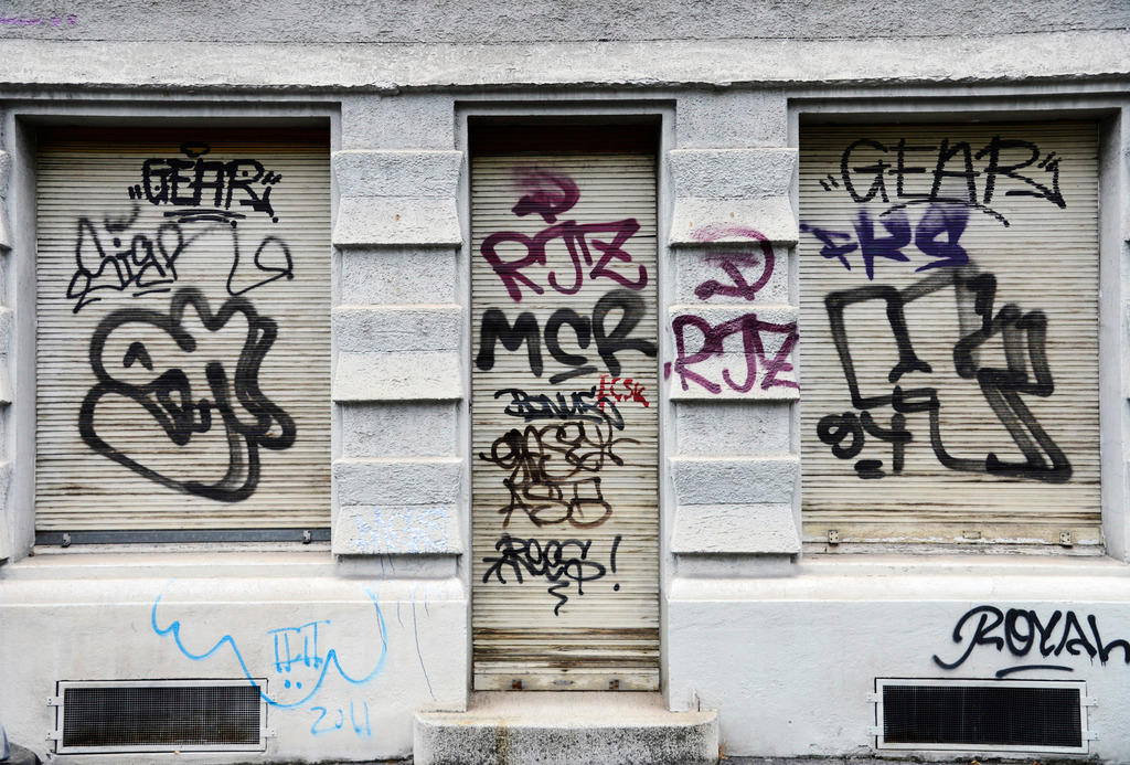 Geschäft in der Stadt Zürich mit heruntergezogenen Storen, die versprayt sind