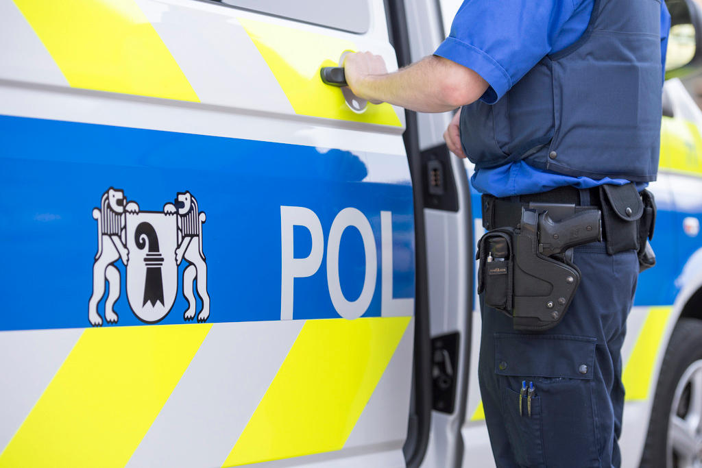 A policeman stands in front of a police car of the cantonal police Basel City
