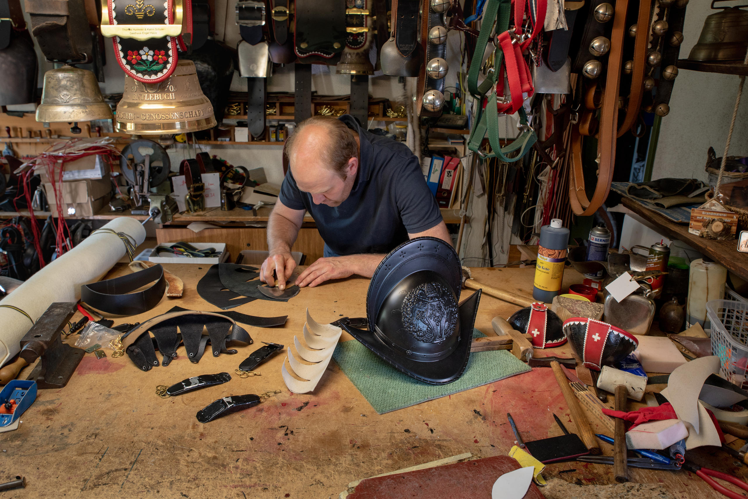 Artesão trabalha atentamente num capacete em sua oficina