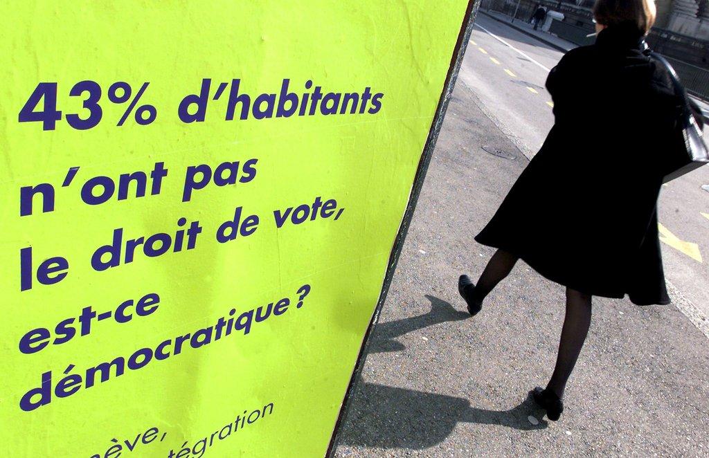 woman walking past a public billboard asking if it is democratic that only 43% of residents in Geneva have the right to vote