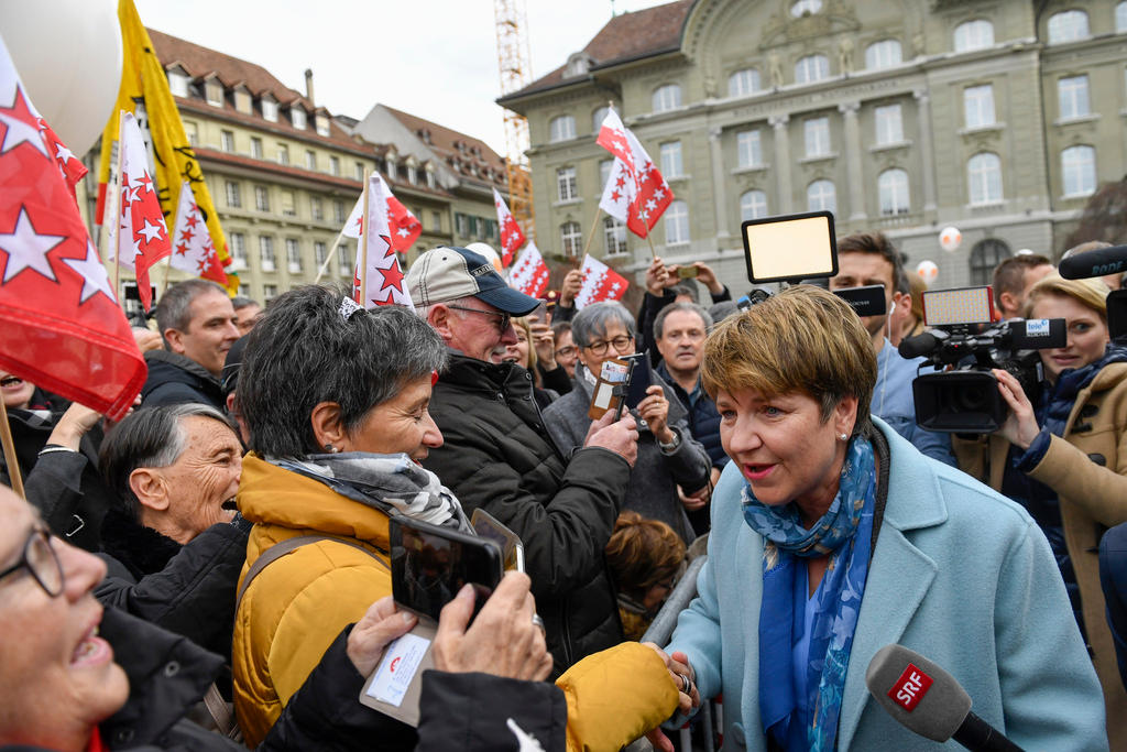 Eine Frau spricht mit Menschen, die sie umringen.