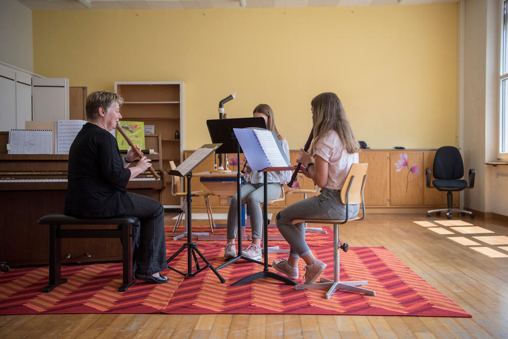 Musiklehrerin und zwei Schülerinnen spielen Blockflöte