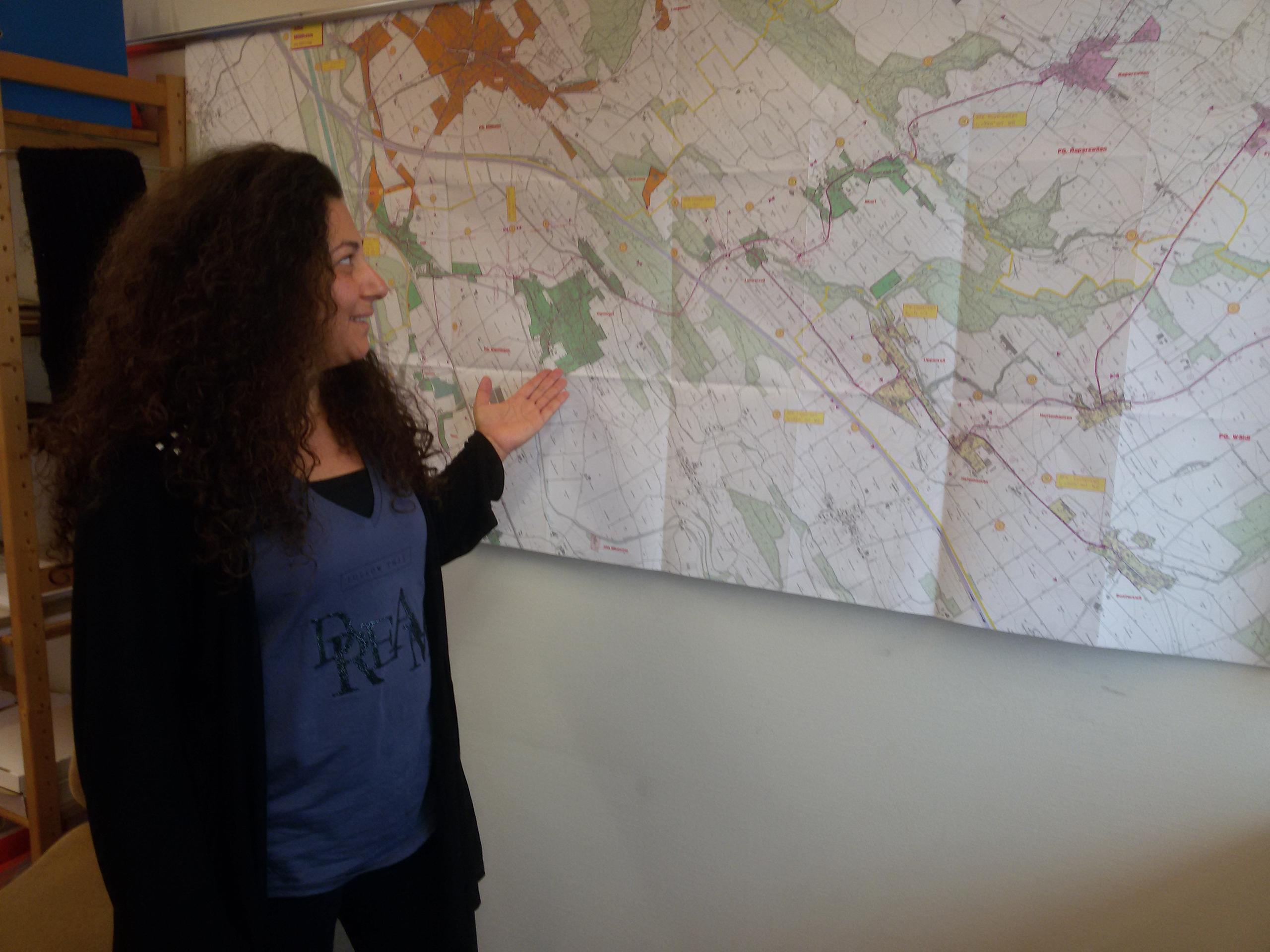 امرأة تقف أمام خريطة مثبتة على جدار