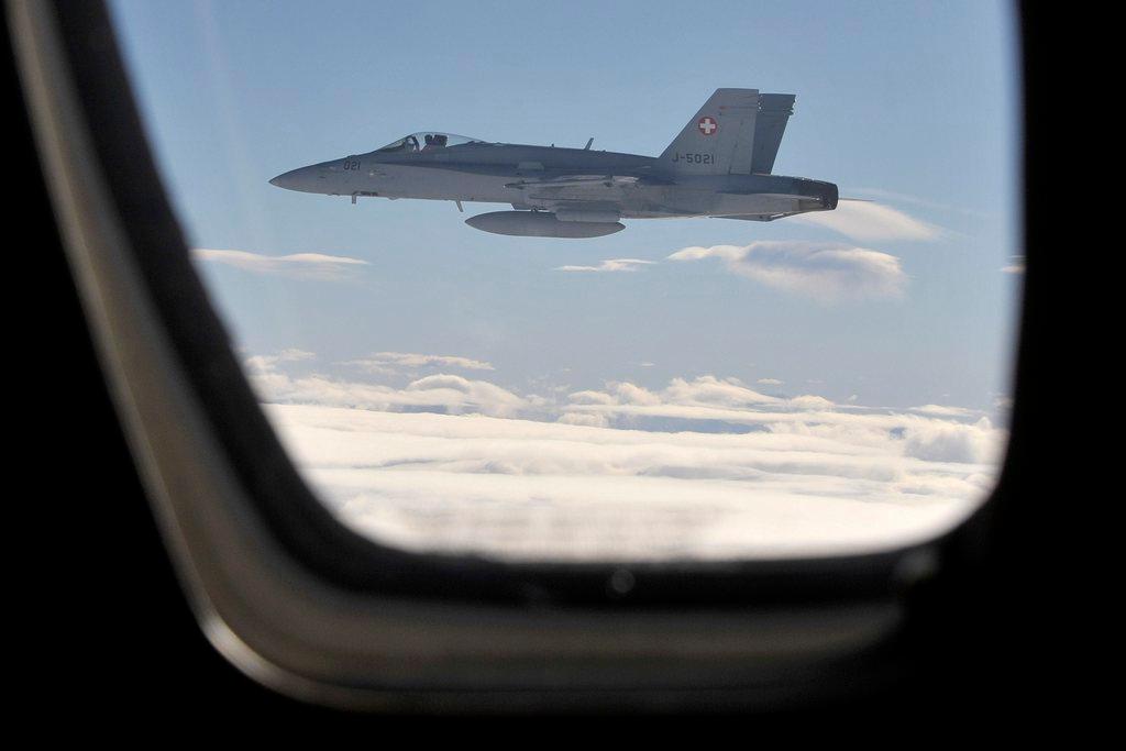 A FA-18 Hornet from the Swiss Army flies next to a civil plane