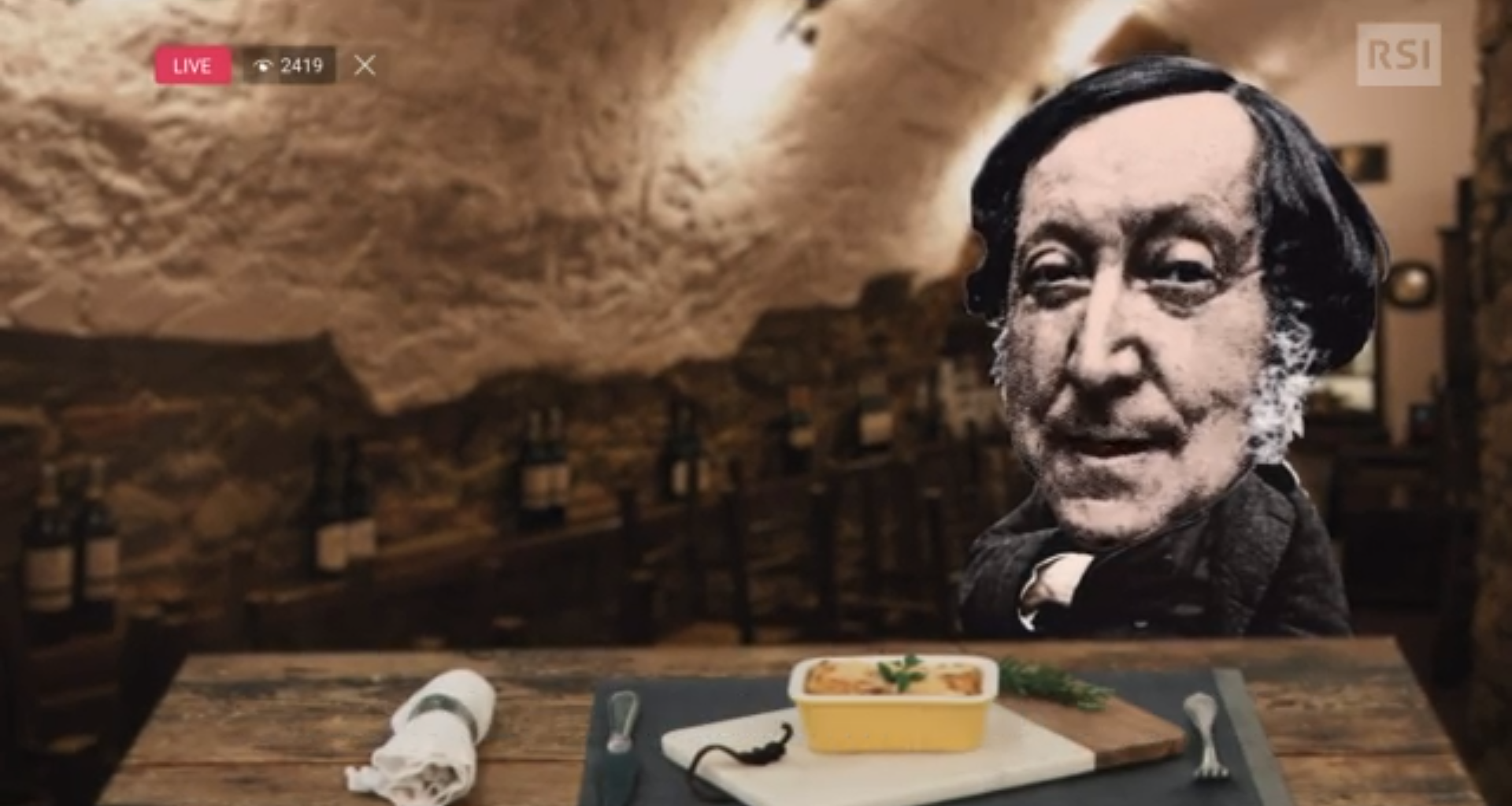 Figura di Rossini montata (stile collage) di fronte a una tavola imbandita con una vaschetta di maccheroni al forno