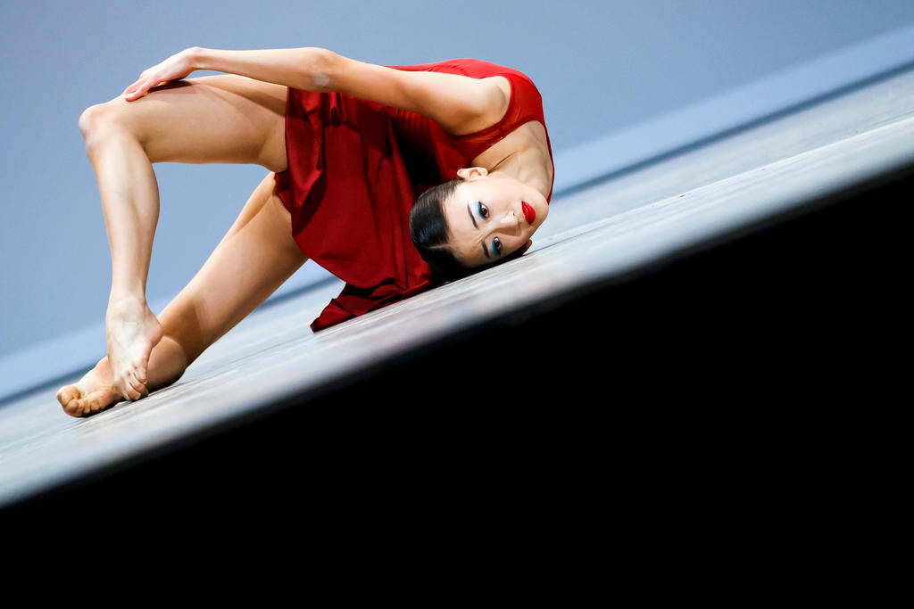 Tänzerin in rotem Kleid in verdrehter Haltung am Boden