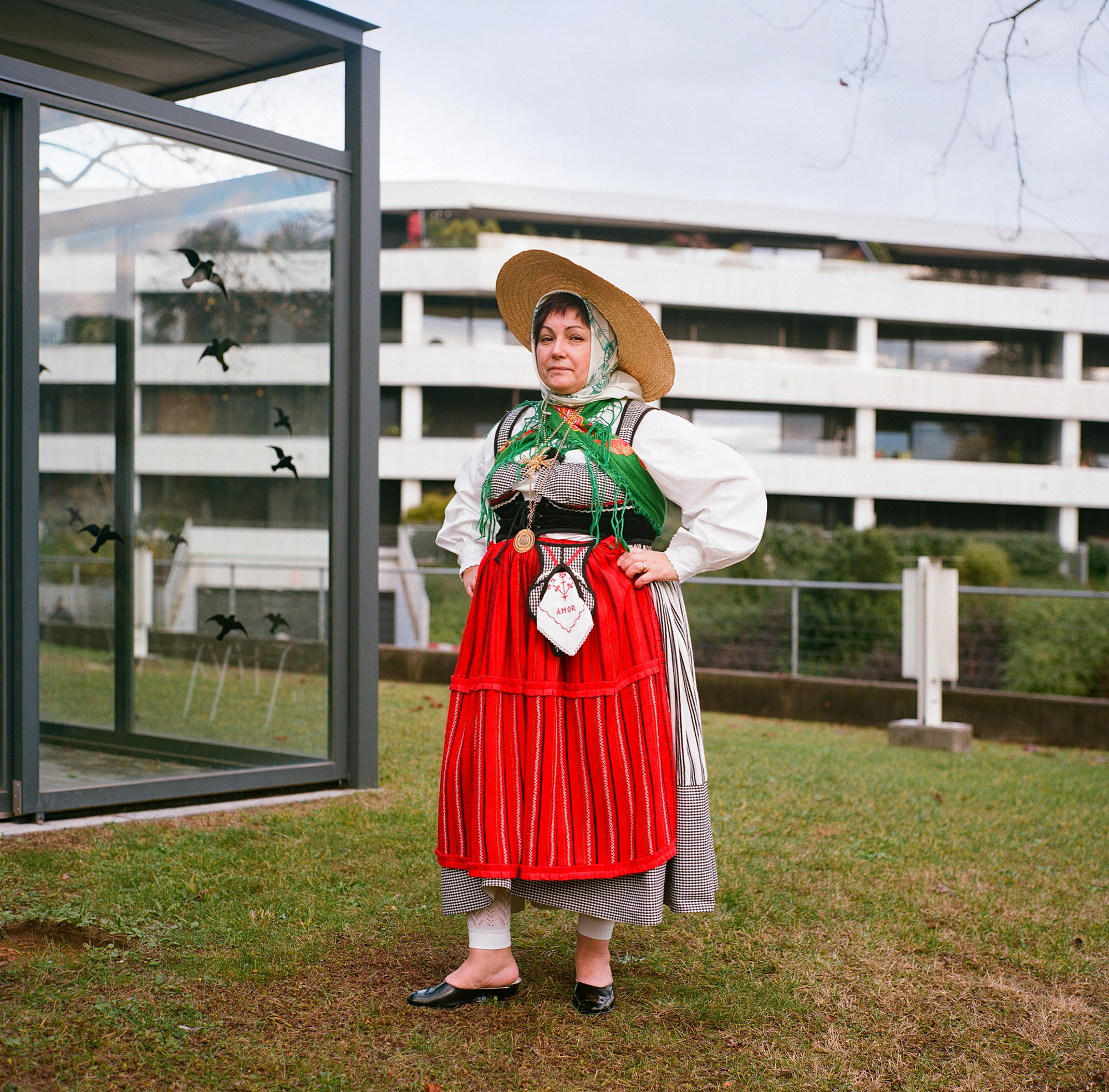 Mujer con vestimenta típica de Portugal: sombrero amplio de palma, vestido con tirantes sobre blusa blanca y amplio mandil rojo