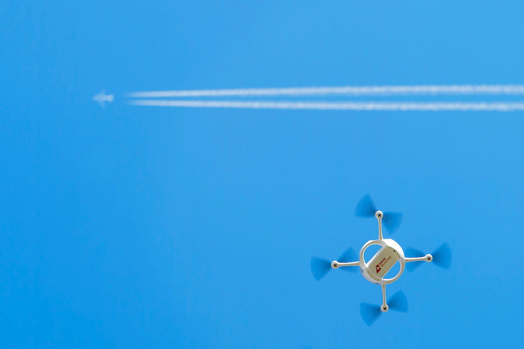 A drone flies in front of an airplane high above in the sky