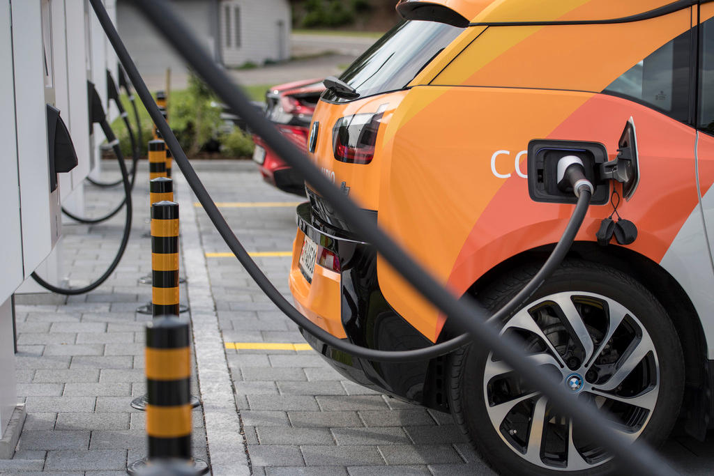 Parte posteriore della fiancata di un automobile, con cavo elettrico connesso a una colonnina di una serie di colonnine