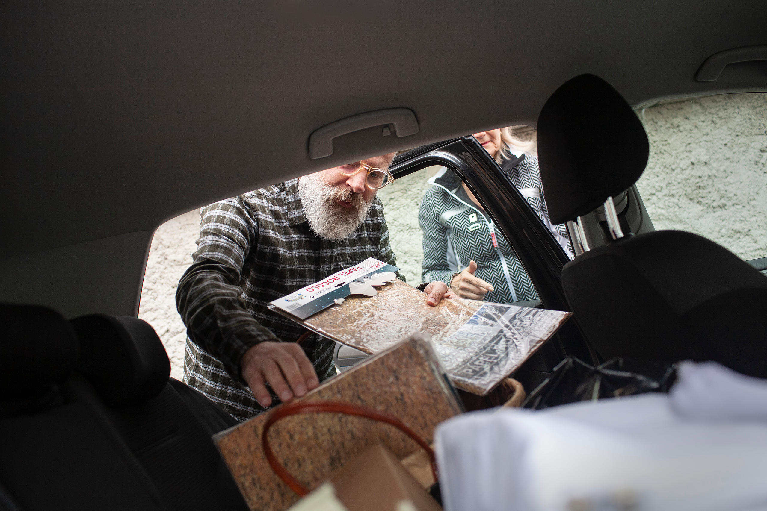 un uomo estrae dei fogli plastificati da un auto