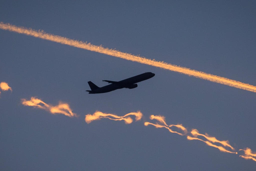 طائرة في السماء وسط مسارات طائرتين نفاثتين مرسومين بما يصدر عنهما من دخان