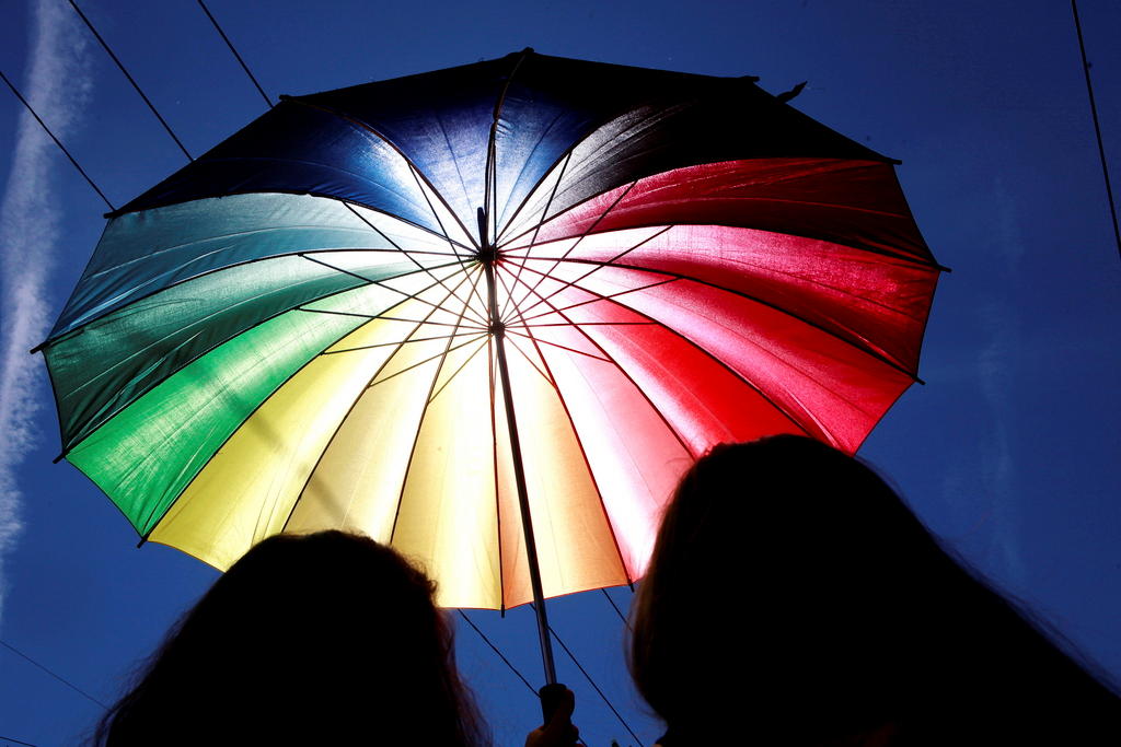 Two people under a rainbow umbrella