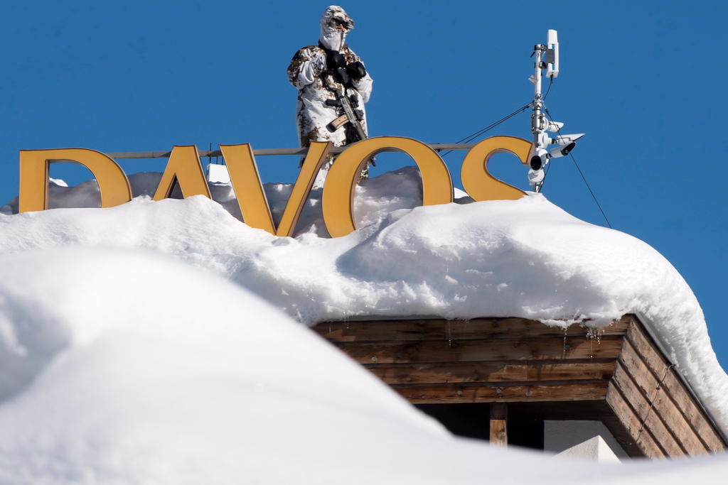 Imagen de la parte superios de un inmueble lleno de nieve con el letrero Davos y un guardia armado
