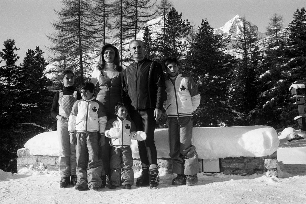 Eine Familie mit vier Kindern posiert für ein Bild im Schnee, im Hintergrund sind Berge.