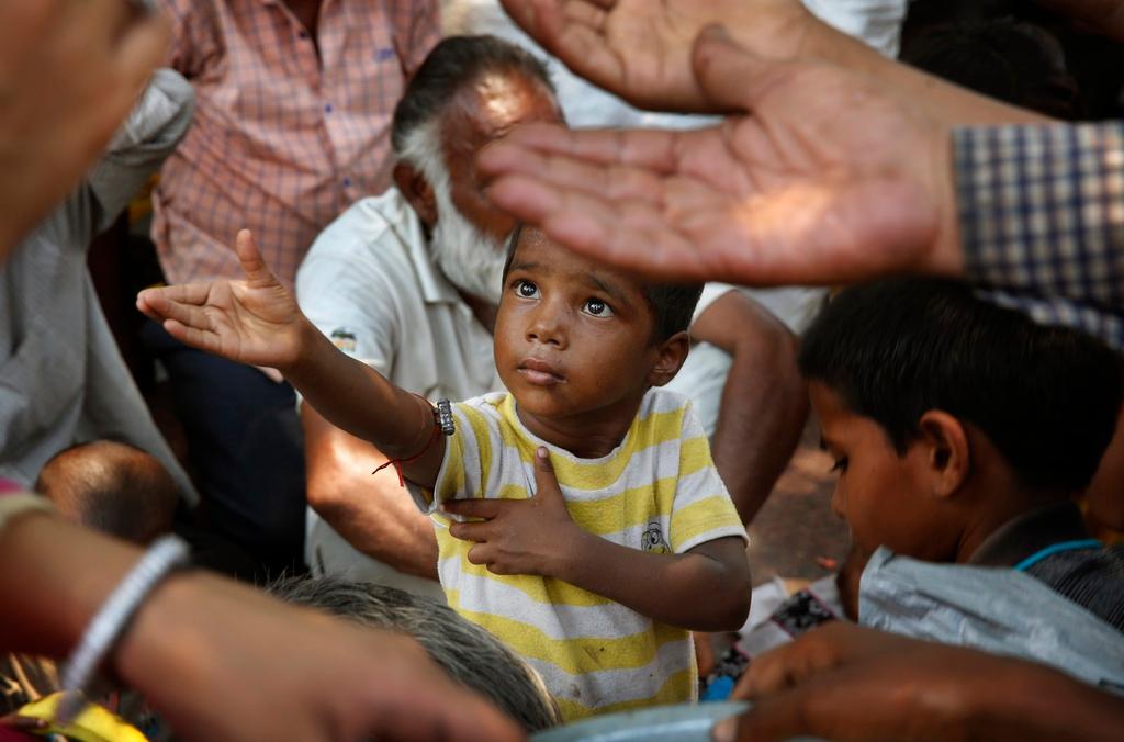  child stretches arms to receive free food being distributed in India