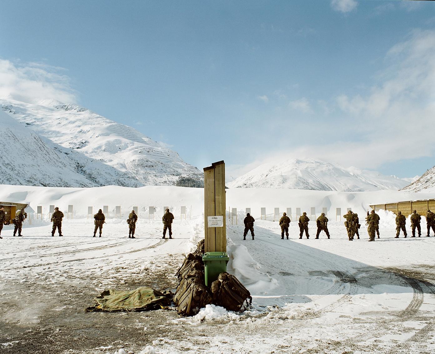 Militärische Schiessanlage im Schnee mit Soldaten in REhi und Glied