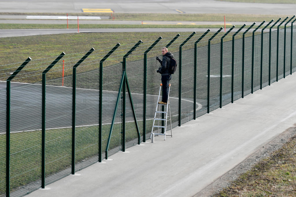 Un hombre subido en una escalera observa a través de un enrejado