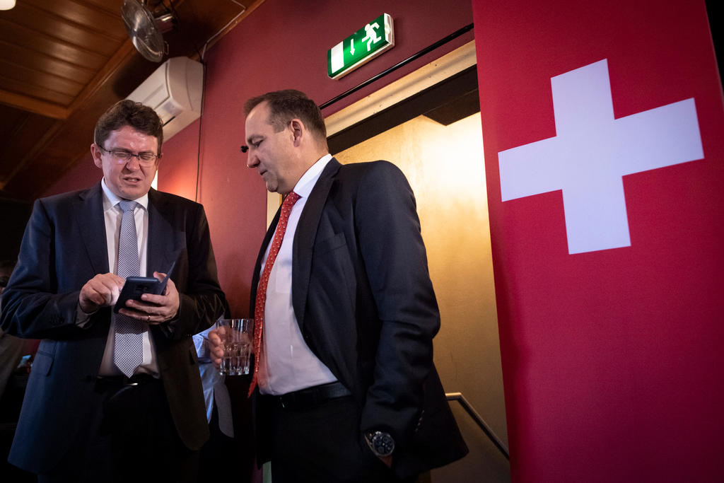 Two senior members of the Swiss People s Party next to a Swiss flag